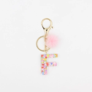 Détail du porte-clés lettre F en résine avec pompon rose et paillettes de cœur