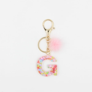 Détail du porte-clés lettre G en résine avec paillettes cœur et pompon en fourrure rose