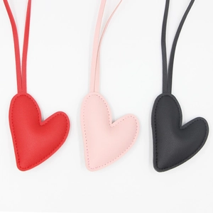 Detail of heart-shaped faux leather keychains with stitching in red, pink, and black