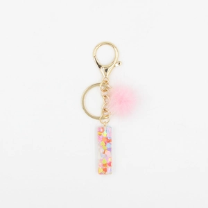Détail du pompon rose et du porte-clés en résine avec des paillettes en forme de cœur