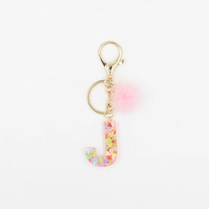 Détail du porte-clés lettre J en résine avec paillettes cœur et pompon en fausse fourrure
