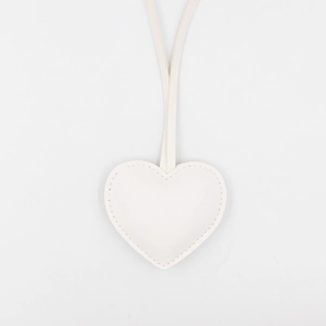 Close-up of white heart-shaped leather keychain with decorative stitching and long strap