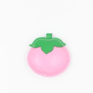 Detail of peach-shaped PU leather pendant featuring pink stitching and green leaf accent