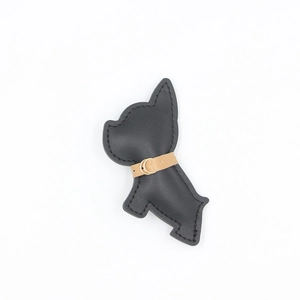 Dettaglio portachiavi bulldog francese in pelle nera con fibbia dorata e trama