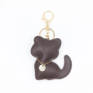 Détail d'un porte-clés chat en cuir marron foncé avec attaches dorées élégantes