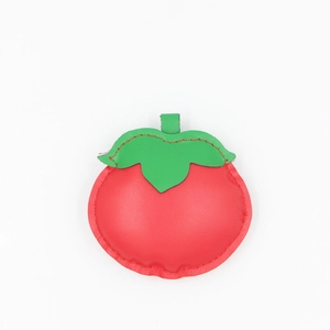 Detail of red persimmon leather pendant with green leaves and premium stitching