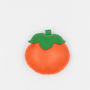 Close-up of orange persimmon-shaped PU leather bag charm with green leaf and fine stitching