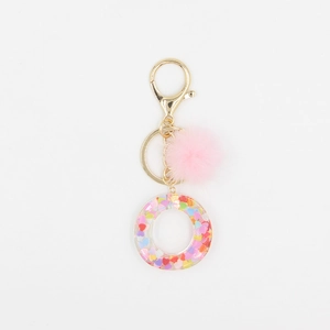 Détail du porte-clés pompon rose avec anneau en résine rempli de paillettes de cœur