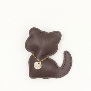 Gros plan d'un porte-clés chat en cuir marron avec chaîne dorée et pendentif gravé