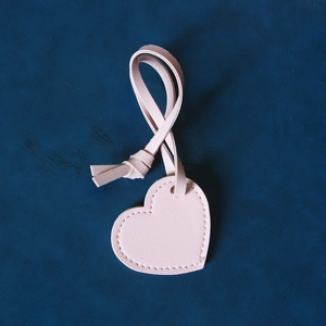Detail of light pink heart leather pendant with litchi texture and matching stitching