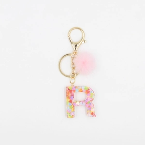 Détail du porte-clés lettre R en résine avec paillettes et pompon en fourrure de vison