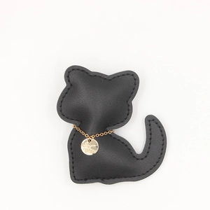 Détail d'un porte-clés chat en cuir noir avec chaîne dorée et pendentif gravé élégant
