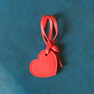 Handmade red leather heart keychain charm with stitched edges on blue background
