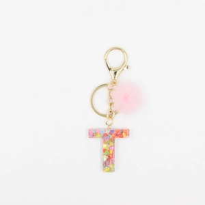 Vue détaillée du porte-clés lettre T en résine avec pompon rose et paillettes colorées