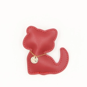 Gros plan détaillé d'un pendentif chat en cuir rouge avec chaîne dorée et médaillon