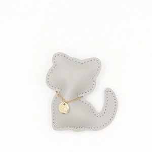 Détail d'un pendentif chat en cuir gris avec surpiqûres et médaillon doré brillant