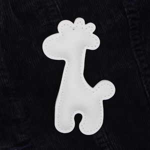 Close-up of a white giraffe PU leather pendant with detailed stitching on blue fabric