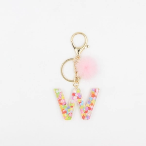 Détail du porte-clés en résine lettre W avec paillettes roses et pompon pelucheux