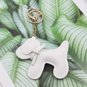 Détail d'un porte-clés chiot en similicuir blanc avec anneau doré et coutures fines de bord