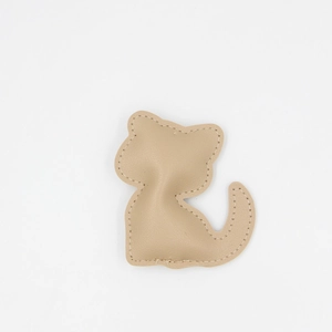 Détail d'un porte-clés chat en similicuir beige avec des coutures blanches de précision
