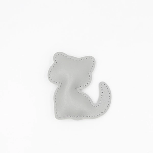 Détail du porte-clés chat en cuir gris avec texture grainée et coutures précises