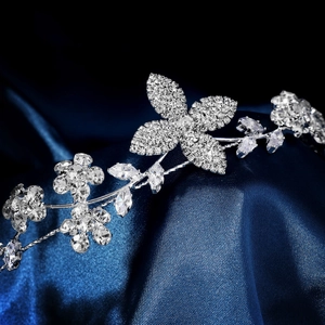 Détail macro du bandeau de fleurs argentées avec zircons sur satin bleu