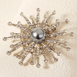 Elegant snowflake brooch with silver pearl and radiant rhinestones on white background