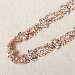 Détails macro du bandeau de mariée montrant les chaînes dorées et le sertissage de strass