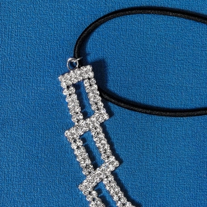 Gros plan du pendentif rectangulaire en strass sur un bandeau noir très élastique