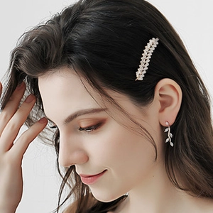 Détail de la pince à cheveux feuille et boucles d'oreilles avec strass brillants sur modèle