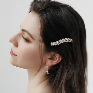 Détail de la pince à cheveux feuille argentée et boucles d'oreilles en zircon sur le modèle