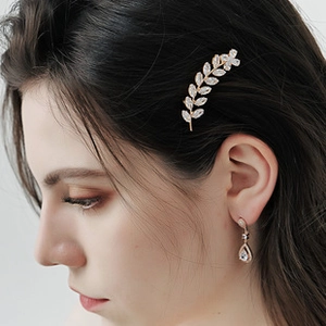Détail de la pince à cheveux en forme de feuille et boucles d'oreilles en strass blancs