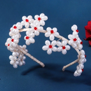 Handmade white faux pearl flower headband with red crystal accents on blue background