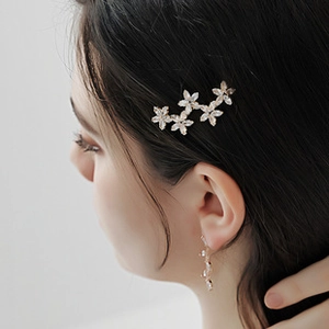 Gros plan d'une pince à cheveux en zircon brillant et boucles d'oreilles fleuries