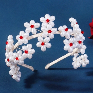Detail of handmade white pearl flower headband with red crystal centers and wrapped base