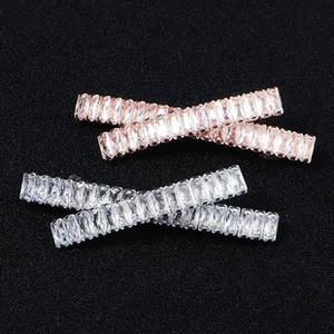 Détail de barrettes croisées or rose et argent avec incrustation de cristal rectangulaire
