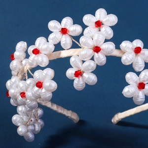 Close-up of handmade white pearl floral headband featuring red crystal centers and beads