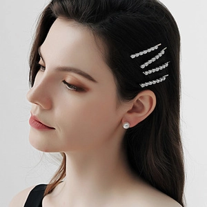 Détail des pinces à cheveux en cristal et boucles d'oreilles perles sur modèle
