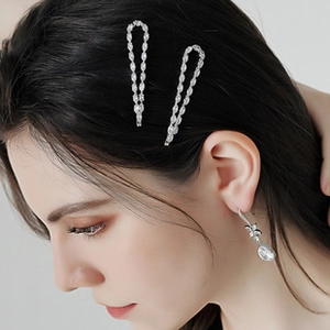 Détail de barrettes en strass et boucles d'oreilles goutte portées par un modèle