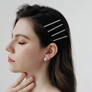 Détail de quatre barrettes en cristal argenté et d'une boucle d'oreille en perle ronde