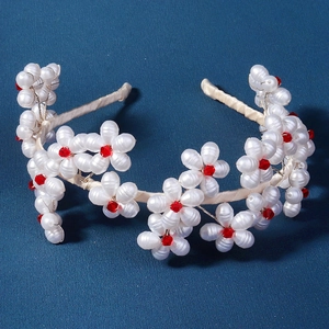 Detail of handcrafted bridal headband with white beaded flowers and red centers