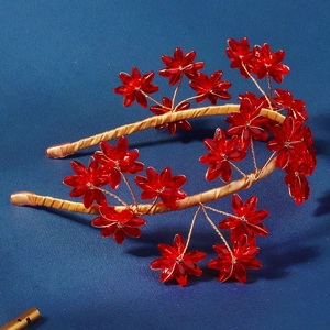 Détail d'un serre-tête fait main avec fleurs en cristal rouge et fil métallique doré