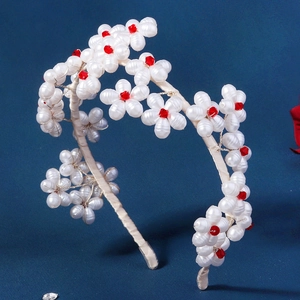Detail of white faux pearl flower headband with red faceted beads on a satin band