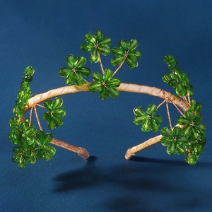 Détail d'un serre-tête artisanal avec fleurs en cristal vert et armature en satin doré