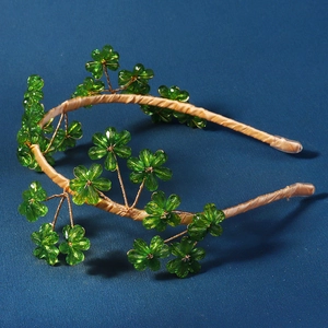 Détail du serre-tête artisanal avec fleurs en cristal vert et ruban de soie dorée