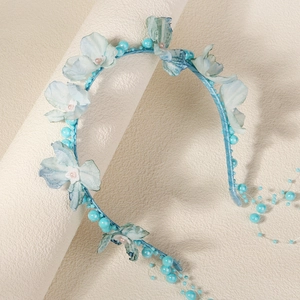 Detail eines hellblauen Blumenstirnbands mit Perlenstickerei und feiner Seidentextur