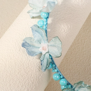 Nahaufnahme eines blauen Blumen-Haarreifens mit Perlen und zarten Stoffblumen für Mädchen