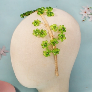 Détail macro du serre-tête artisanal avec fleurs en cristal vert et fils dorés