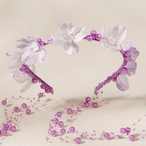 Detail von hellvioletten Seidenblumen und Perlen auf einem romantischen Blumenstirnband
