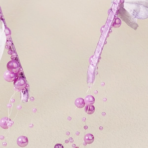 Detailaufnahme des lila Satin-Haarreifens mit irisierenden Perlen und Perlenverzierung